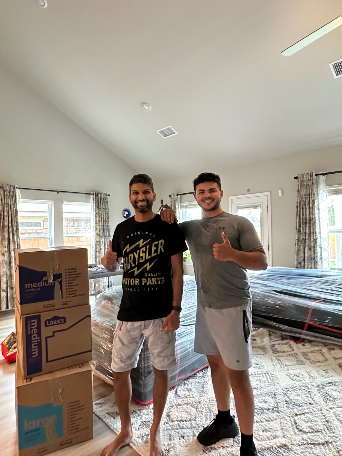 Happy customer and Lovable Movers crew member giving thumbs up next to packed boxes and wrapped furniture